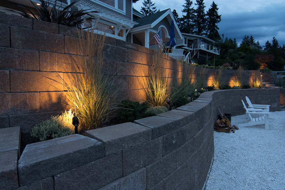 This is an example of a nautical sloped full sun garden in Seattle with a retaining wall and natural stone paving.