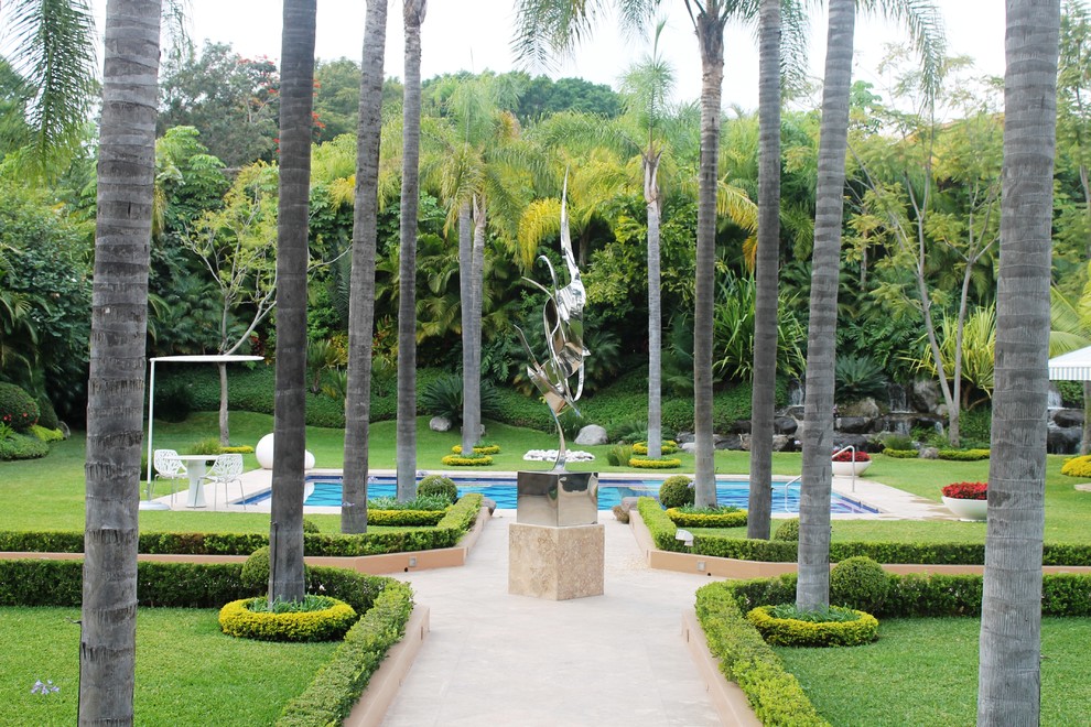 Imagen de jardín tropical en patio trasero con jardín francés