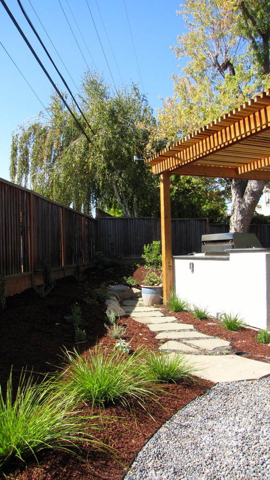 Ejemplo de jardín de secano actual de tamaño medio en patio trasero con fuente, exposición total al sol y gravilla