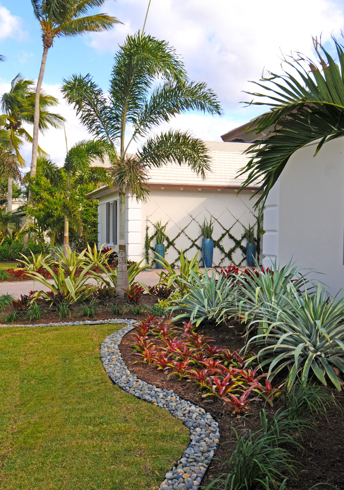 Exempel på en mellanstor exotisk trädgård i delvis sol framför huset, med utekrukor