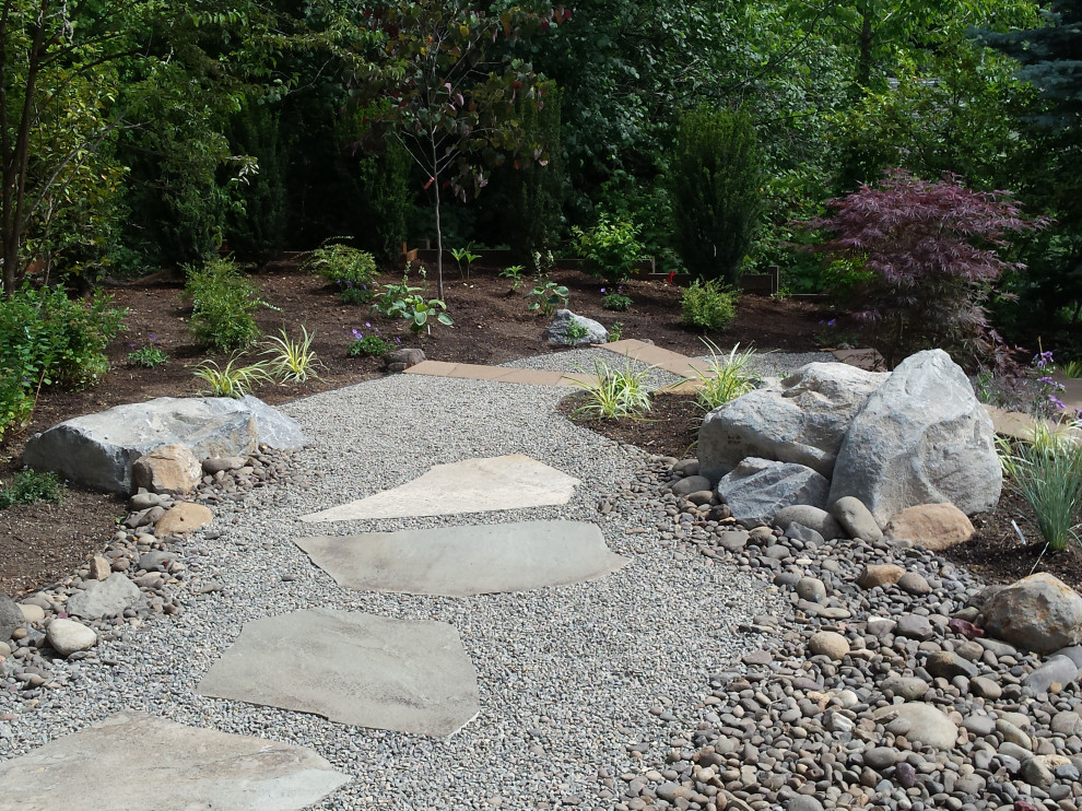 Large world-inspired sloped full sun garden for spring in Portland with a rockery and natural stone paving.