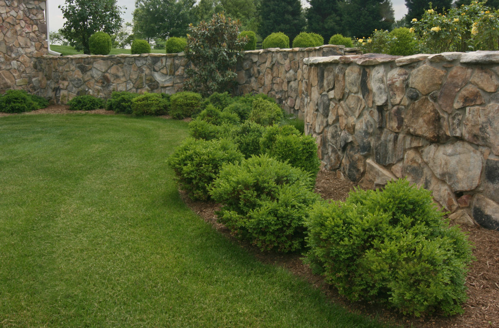 Cette image montre un jardin traditionnel de taille moyenne avec un mur de soutènement, une exposition ensoleillée et des pavés en pierre naturelle.