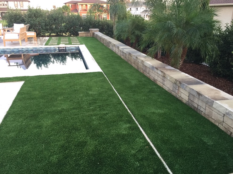 Medium sized world-inspired back formal partial sun garden in Tampa with a retaining wall and mulch.