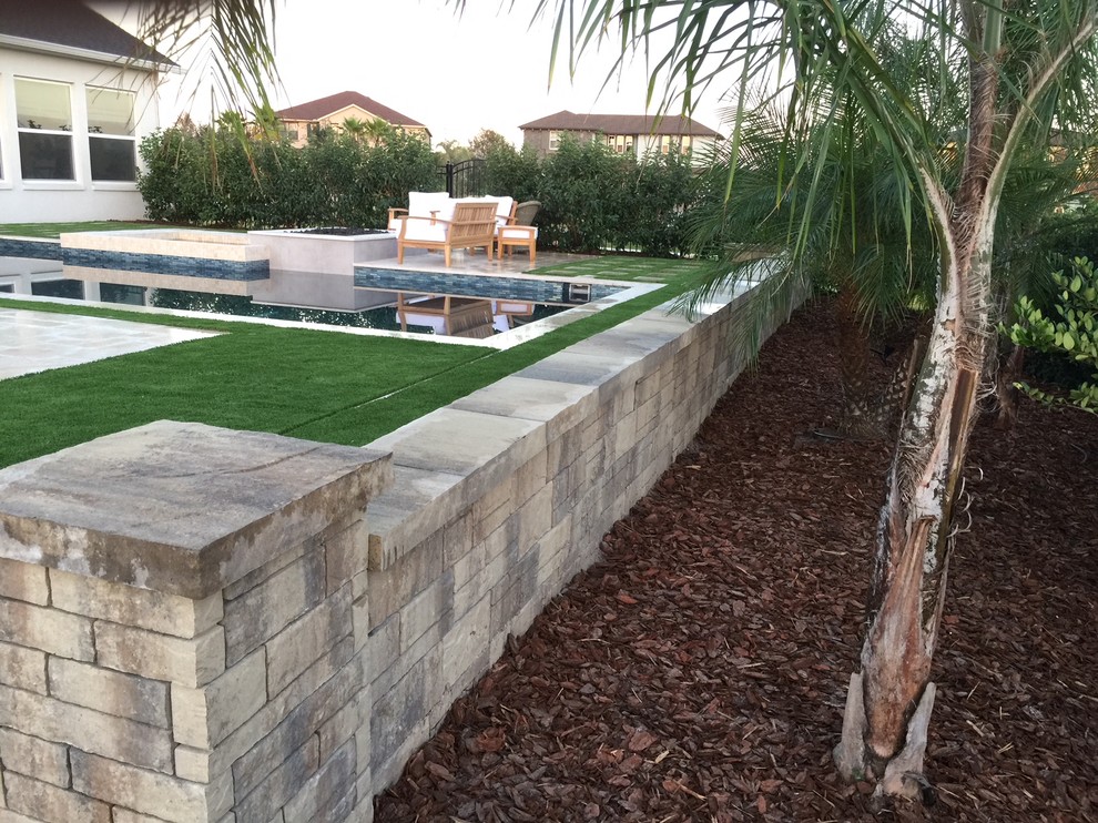 This is an example of a medium sized world-inspired back formal partial sun garden in Tampa with a retaining wall and mulch.