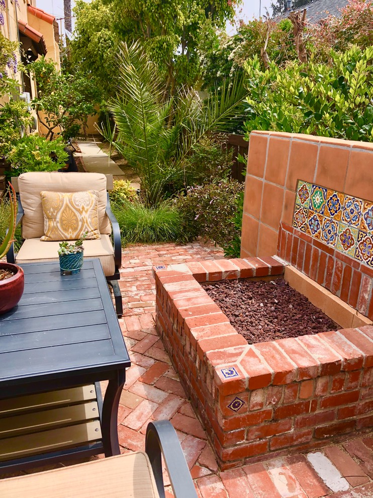 Diseño de jardín de secano mediterráneo de tamaño medio en primavera en patio trasero con brasero, exposición total al sol, adoquines de ladrillo y con madera