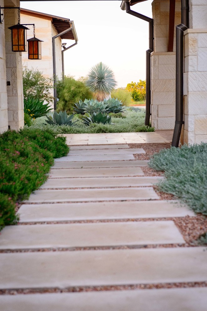 Large modern front xeriscape full sun garden in Austin with natural stone paving and a garden path.