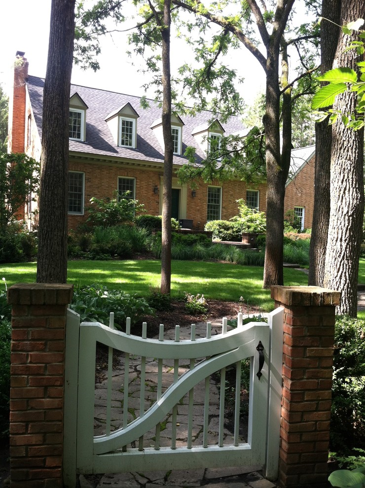 На фото: большой летний регулярный сад на переднем дворе в классическом стиле с садовой дорожкой или калиткой, полуденной тенью и покрытием из каменной брусчатки с