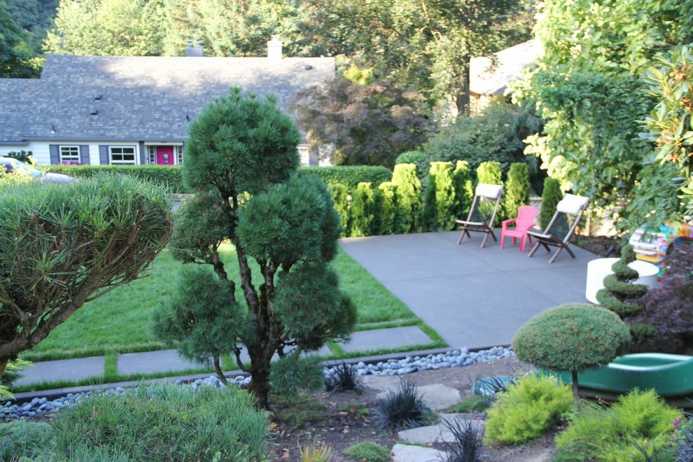 Immagine di un giardino chic esposto a mezz'ombra di medie dimensioni e dietro casa con uno spazio giochi e pavimentazioni in cemento