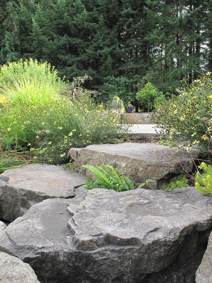 This is an example of a large traditional partial sun backyard stone landscaping in Portland.