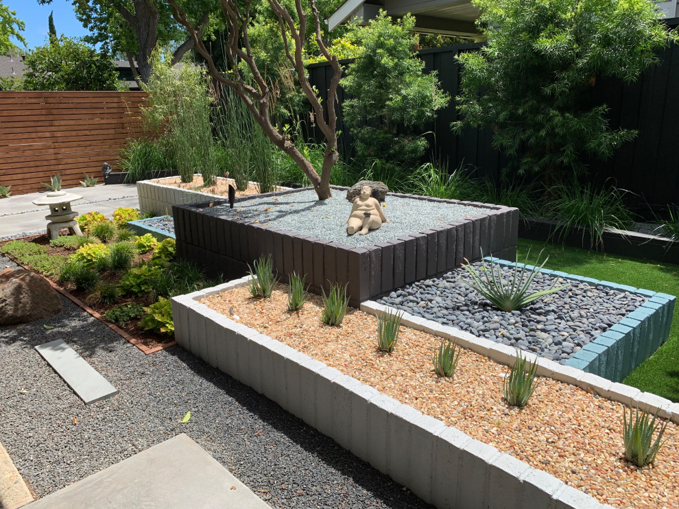 Immagine di un giardino xeriscape minimalista davanti casa con un muro di contenimento e sassi di fiume