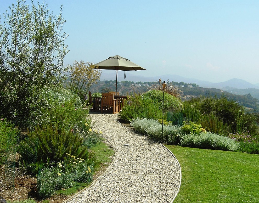 Foto de jardín mediterráneo en patio trasero con gravilla y borde del césped