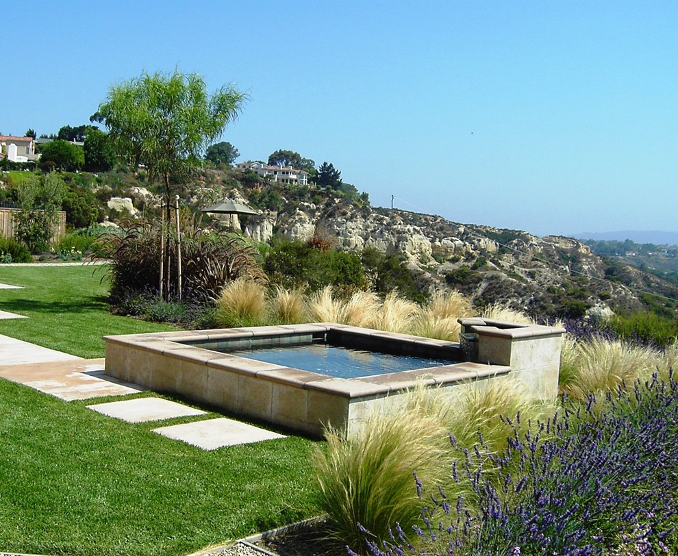 Aménagement d'un grand jardin arrière méditerranéen avec des pavés en béton.