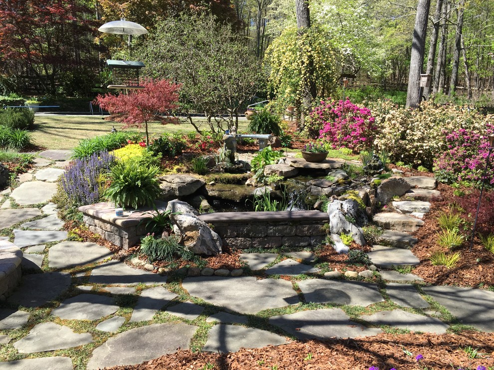 Idée de décoration pour un grand jardin arrière tradition avec un point d'eau, une exposition partiellement ombragée et des pavés en pierre naturelle.