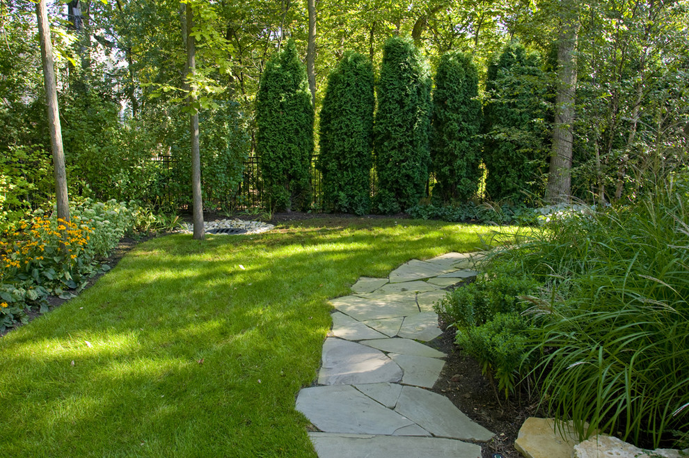 Imagen de camino de jardín clásico en patio trasero con exposición reducida al sol y adoquines de piedra natural