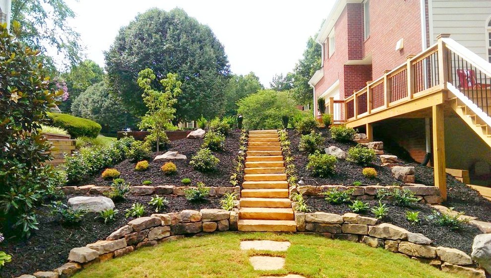 Idee per un grande giardino formale classico nel cortile laterale con pavimentazioni in pietra naturale e un muro di contenimento
