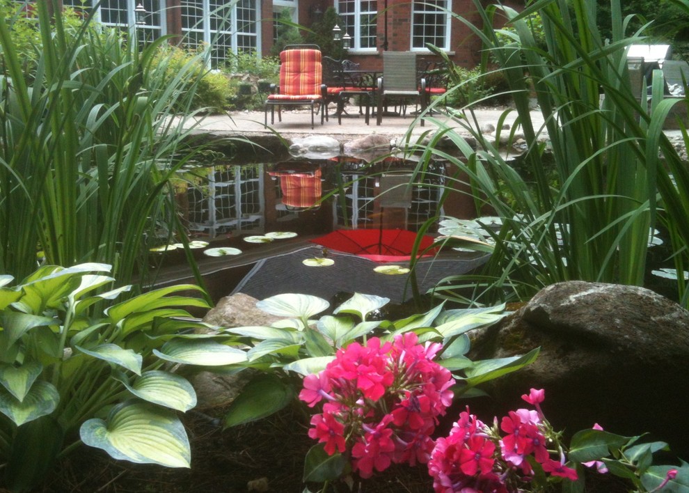Photo of a large traditional full sun backyard stone pond in Montreal for summer.
