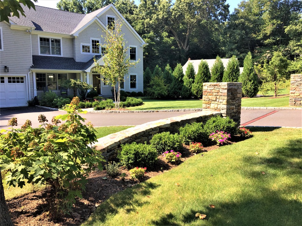 На фото: большой участок и сад на переднем дворе в классическом стиле с мульчированием, подъездной дорогой и полуденной тенью с