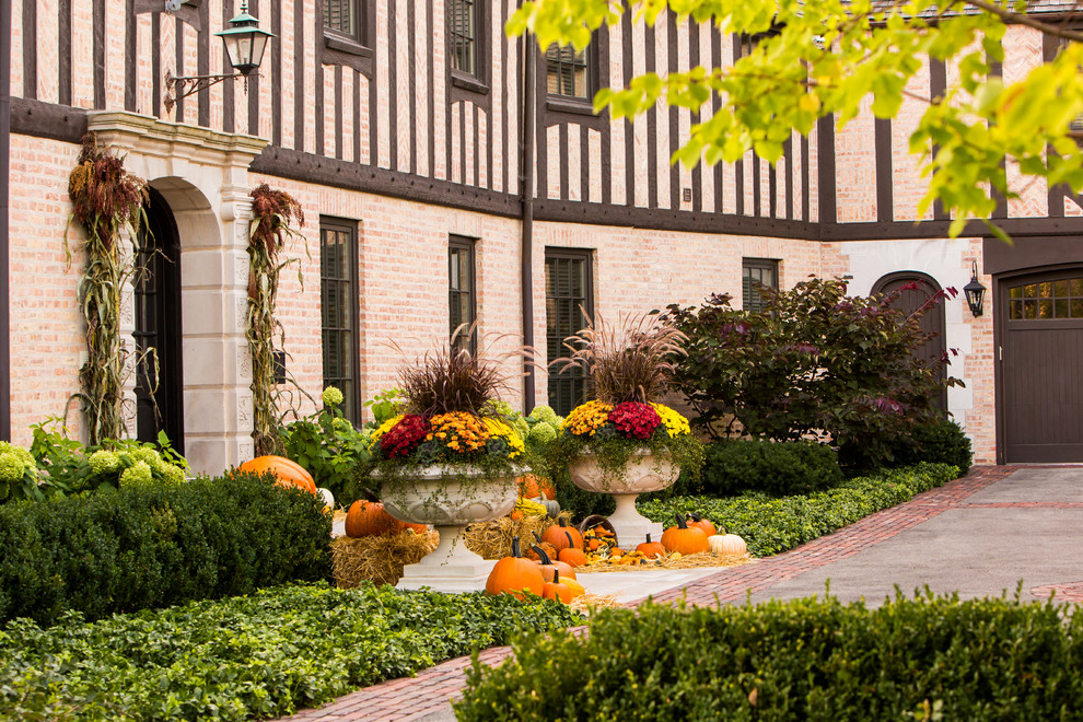 Imagen de jardín clásico grande en otoño en patio delantero con jardín de macetas, exposición total al sol y adoquines de piedra natural
