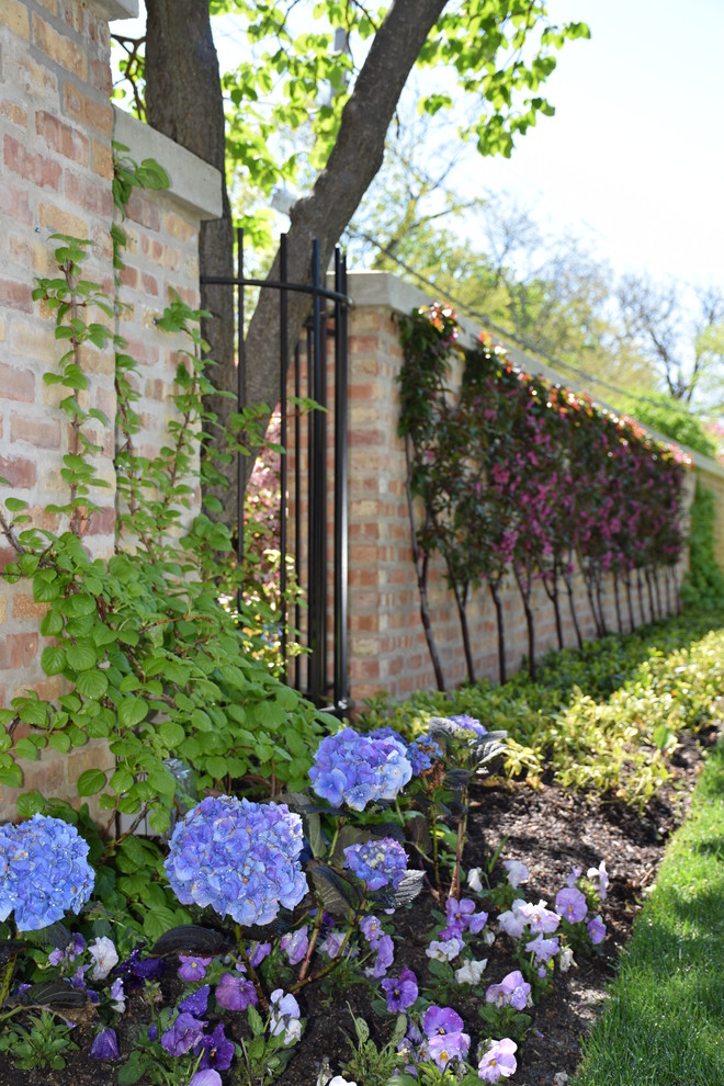 На фото: большой солнечный, весенний регулярный сад на переднем дворе в классическом стиле с хорошей освещенностью с