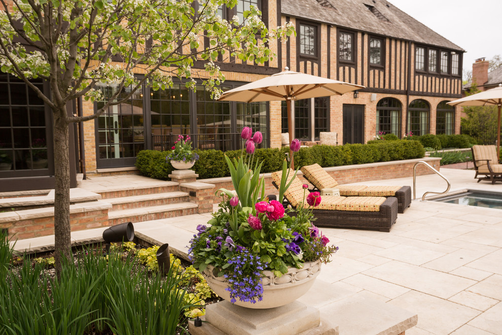 Imagen de jardín clásico grande en primavera en patio trasero con muro de contención, exposición total al sol y adoquines de piedra natural