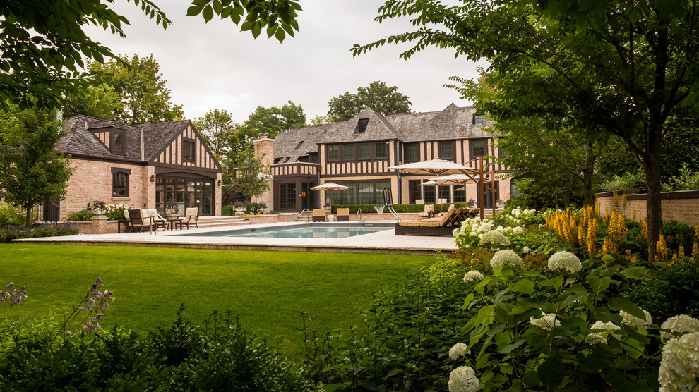 Großer Klassischer Garten im Sommer, hinter dem Haus mit Wasserspiel, direkter Sonneneinstrahlung und Natursteinplatten in Chicago