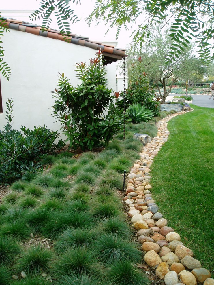 Inspiration for a mid-sized mediterranean partial sun backyard stone landscaping in San Diego with a fire pit for summer.