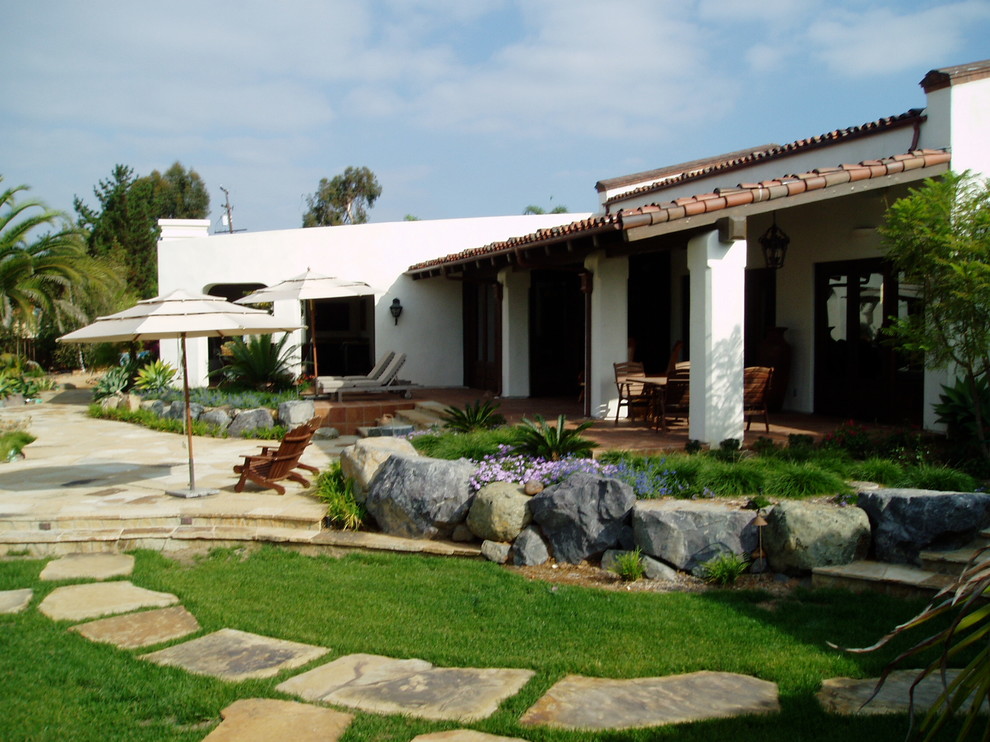 Imagen de jardín mediterráneo de tamaño medio en verano en patio trasero con brasero, exposición parcial al sol y adoquines de piedra natural