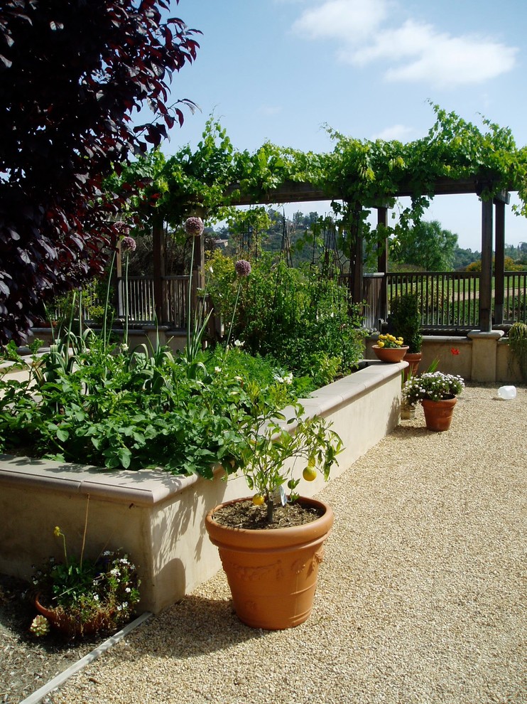 Exempel på en medelhavsstil bakgård i full sol, med en köksträdgård och grus