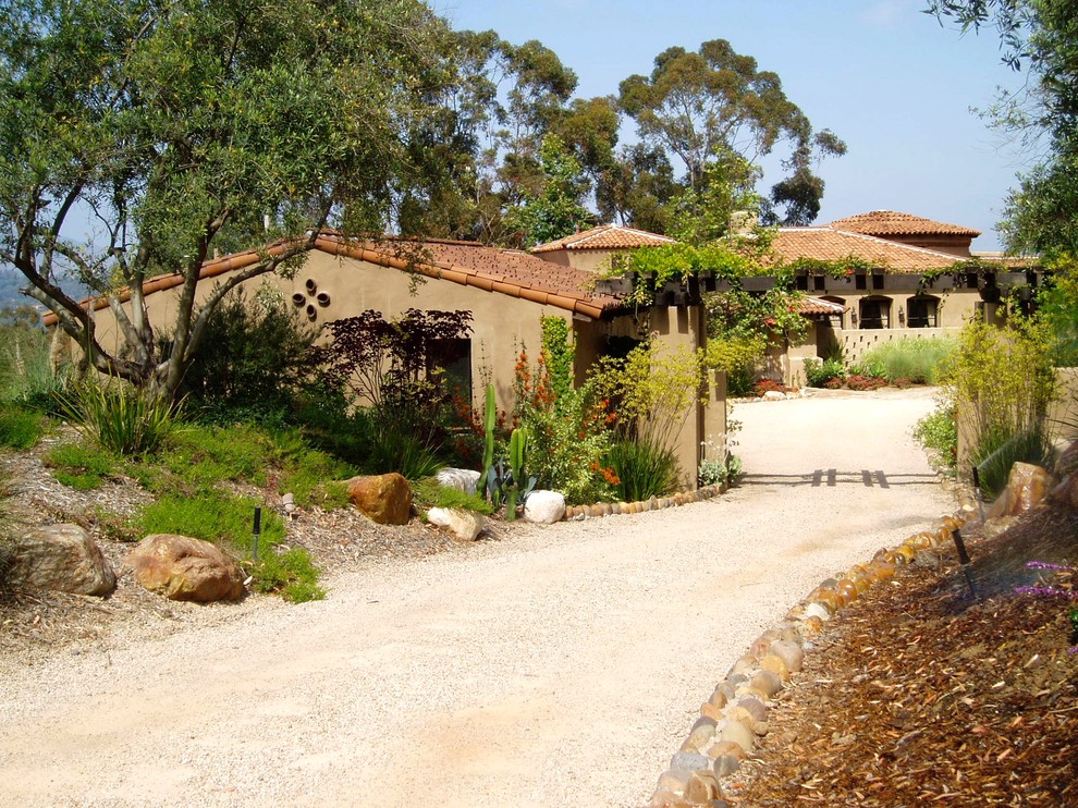 This is an example of a mediterranean courtyard driveway full sun garden in San Diego with gravel.
