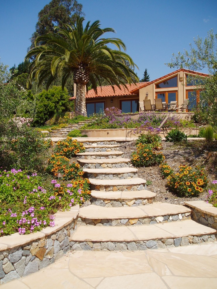 Réalisation d'un jardin méditerranéen avec une exposition ensoleillée, une pente, une colline ou un talus et des pavés en pierre naturelle.