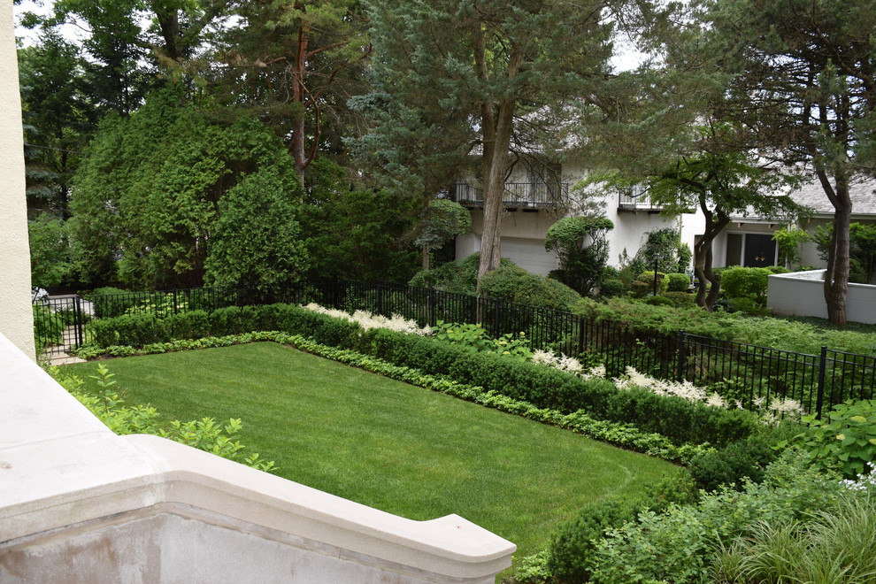 На фото: летний регулярный сад среднего размера на заднем дворе в классическом стиле с полуденной тенью с