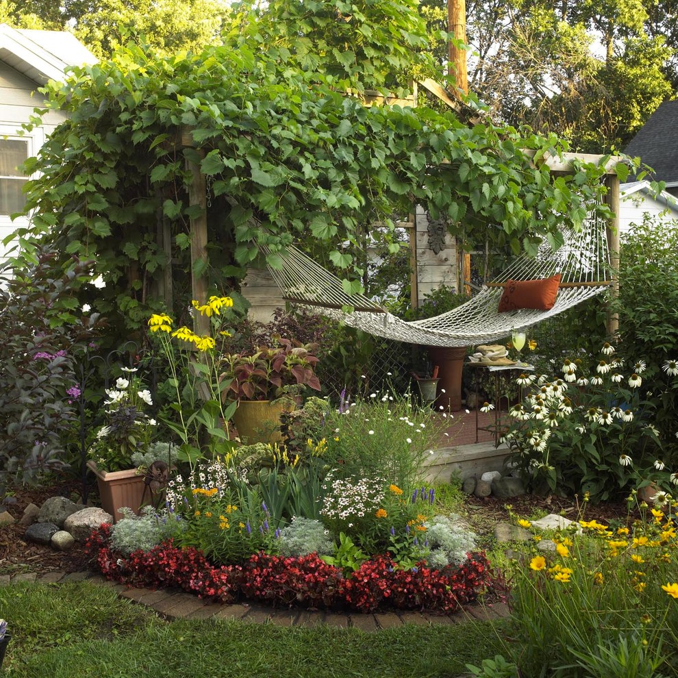 Exemple d'un petit jardin arrière romantique l'été avec une exposition ensoleillée et une terrasse en bois.
