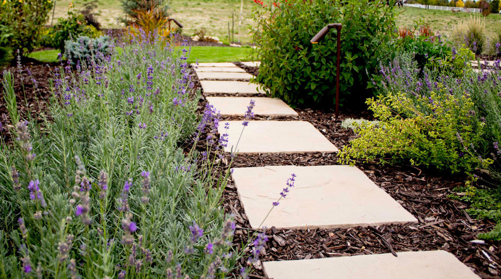 Ejemplo de jardín clásico grande en primavera en patio delantero con jardín francés y adoquines de piedra natural