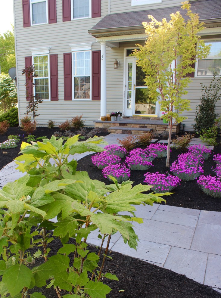 Photo of a medium sized classic front formal full sun garden for spring in New York with a garden path and concrete paving.
