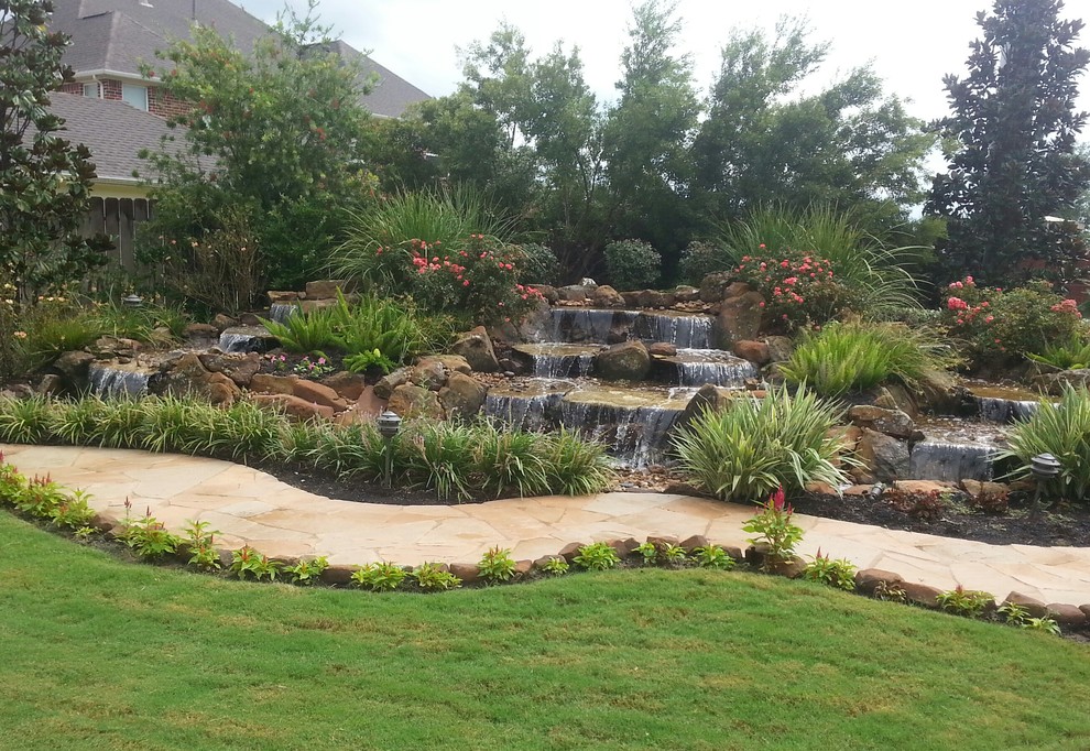 Aménagement d'un très grand jardin arrière avec un point d'eau, une exposition ensoleillée et des pavés en pierre naturelle.