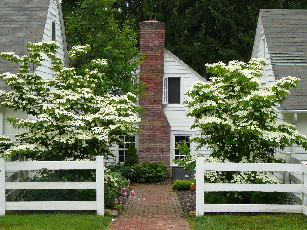 На фото: летний регулярный сад среднего размера на переднем дворе в классическом стиле с мощением клинкерной брусчаткой, полуденной тенью и забором с