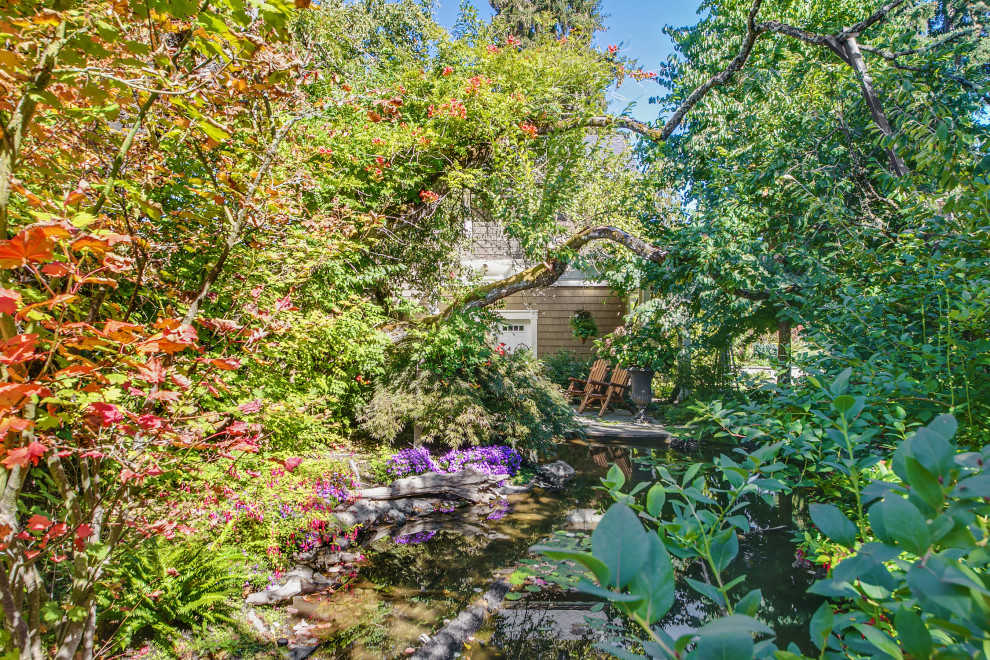 Immagine di un ampio giardino vittoriano esposto in pieno sole davanti casa con sassi di fiume