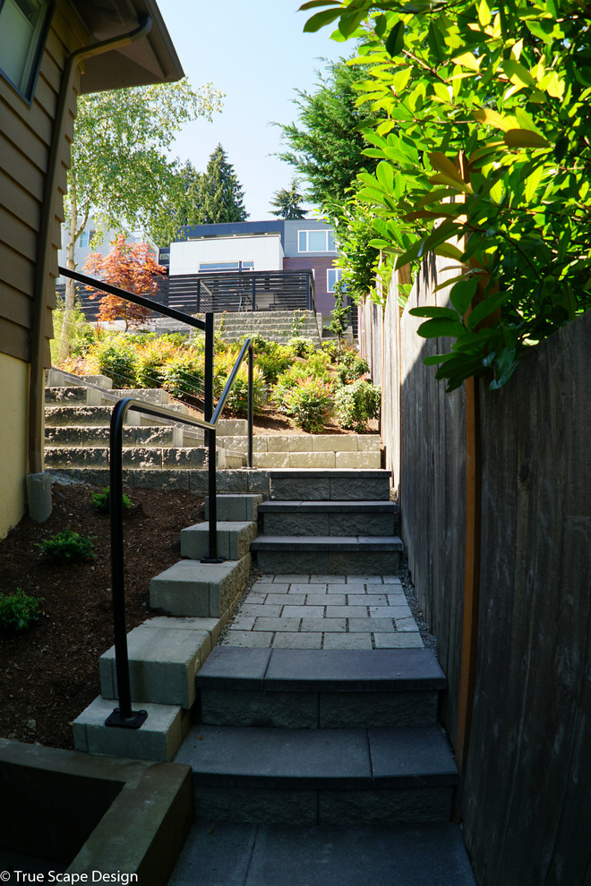 На фото: солнечный, летний участок и сад среднего размера на боковом дворе в стиле модернизм с подпорной стенкой, хорошей освещенностью и мощением тротуарной плиткой с