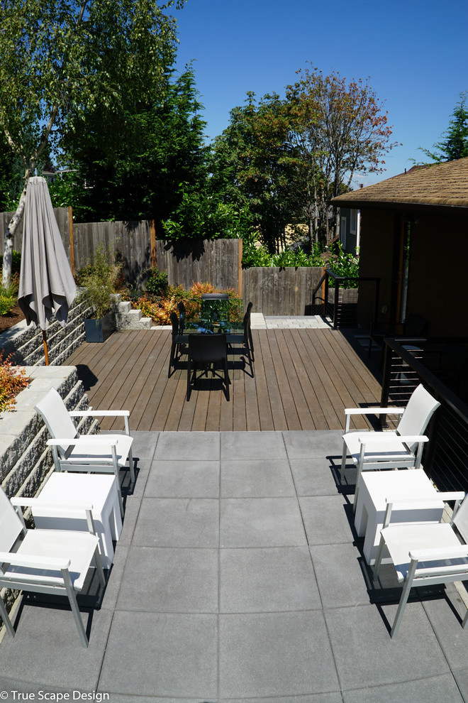 Modelo de jardín de secano minimalista de tamaño medio en primavera en patio trasero con muro de contención, exposición total al sol y entablado
