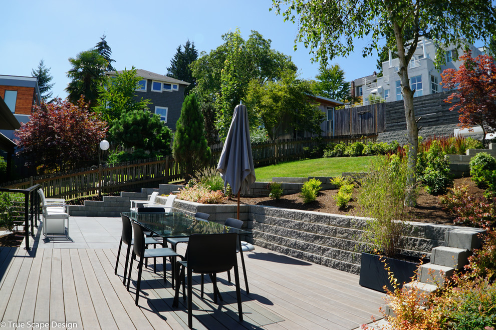 Inspiration for a mid-sized modern drought-tolerant and full sun hillside retaining wall landscape in Seattle with decking for summer.