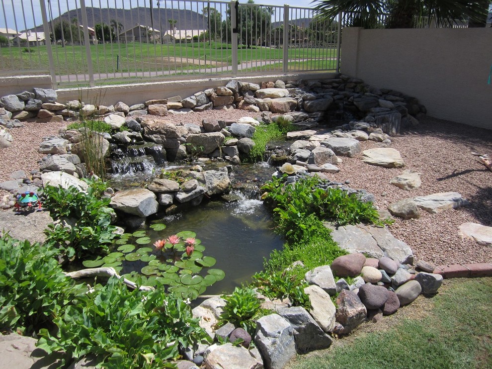 Modelo de jardín mediterráneo grande en patio trasero con estanque y exposición parcial al sol