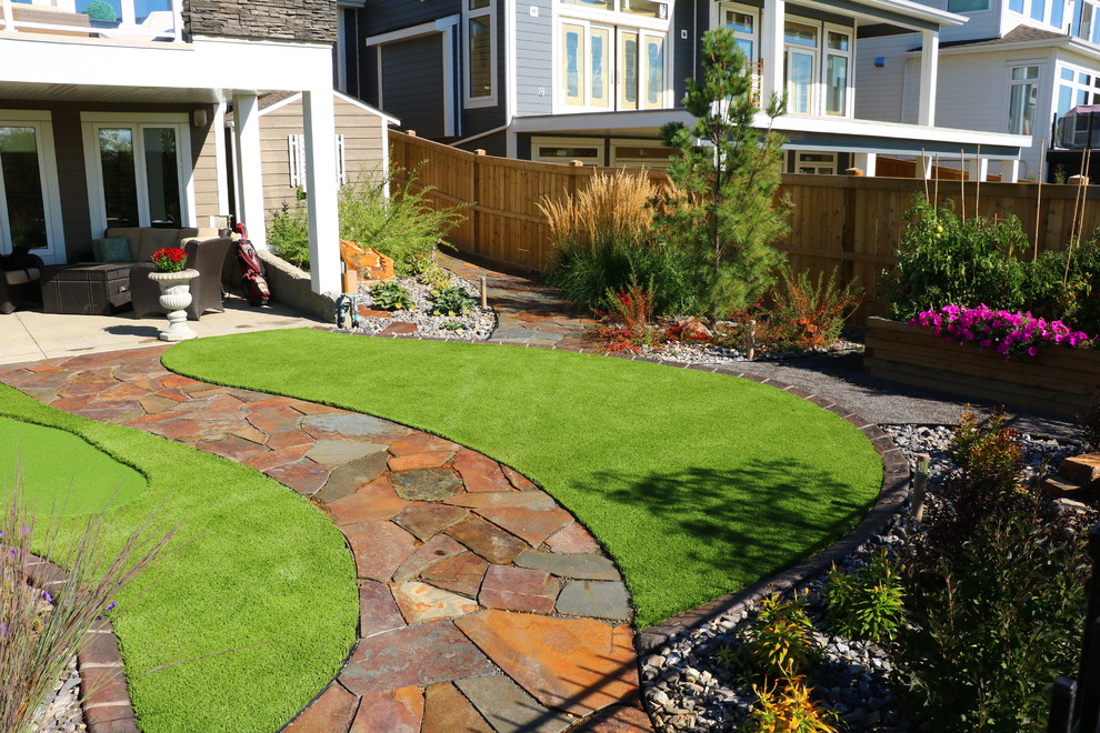 Photo of a mid-sized rustic full sun backyard stone landscaping in Edmonton for summer.