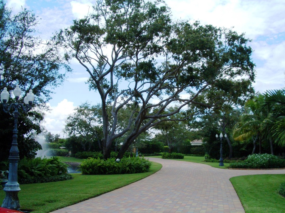 Inspiration for a large transitional partial sun front yard brick driveway in Miami.