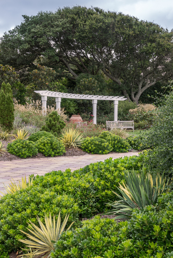 На фото: огромный солнечный, летний регулярный сад на внутреннем дворе в морском стиле с садовой дорожкой или калиткой, хорошей освещенностью и мощением клинкерной брусчаткой