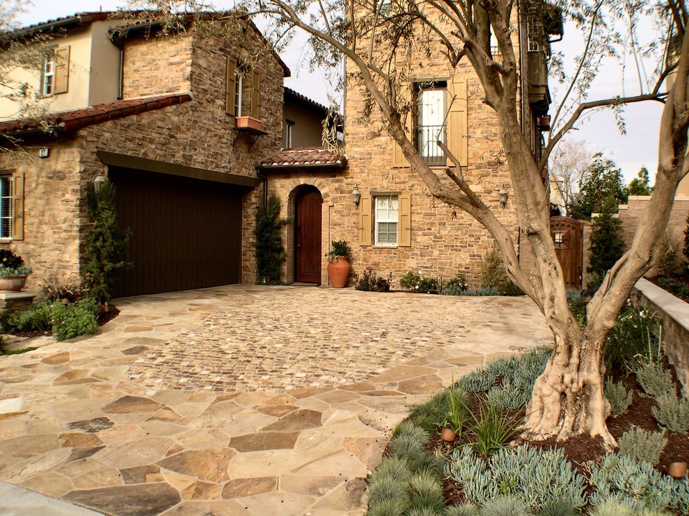 Inspiration for a large country front driveway garden in Orange County with a retaining wall and natural stone paving.