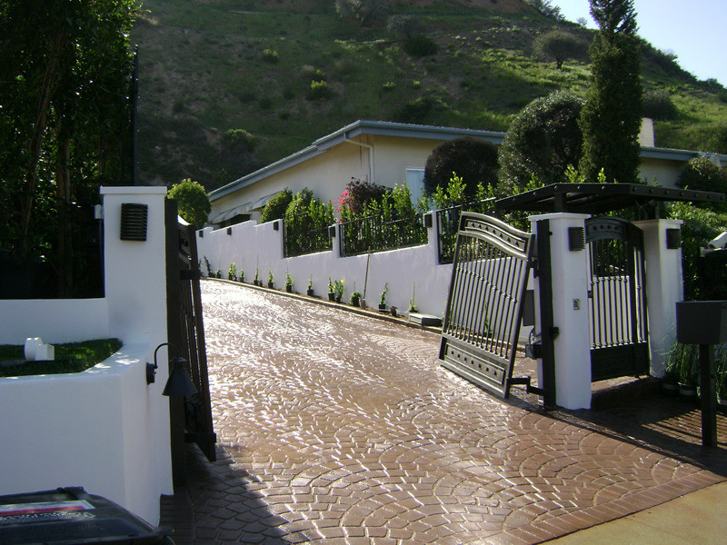 Großer Mediterraner Garten mit Auffahrt, direkter Sonneneinstrahlung und Pflastersteinen in Los Angeles