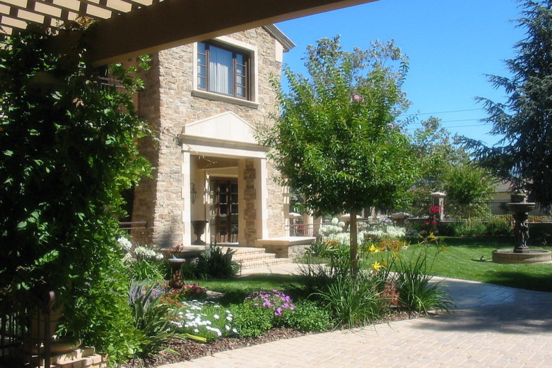 Foto de jardín clásico grande en primavera en patio delantero con exposición total al sol y adoquines de ladrillo