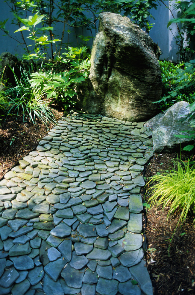 Imagen de jardín clásico de tamaño medio en patio trasero con exposición parcial al sol, fuente y adoquines de piedra natural