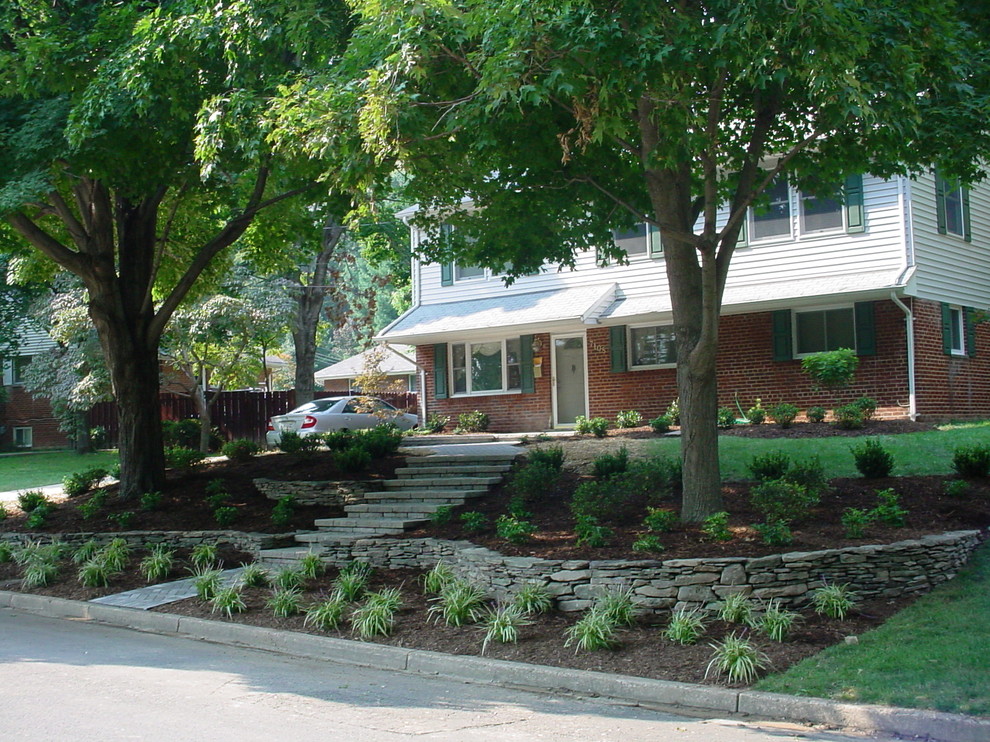 Large classic front driveway fully shaded garden for spring in DC Metro with a retaining wall and natural stone paving.