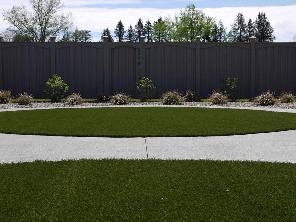 Exemple d'un jardin arrière chic de taille moyenne avec une exposition partiellement ombragée et des pavés en béton.